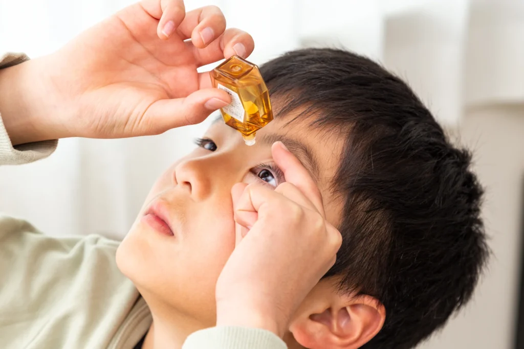 Boy having eye drops put into his eye