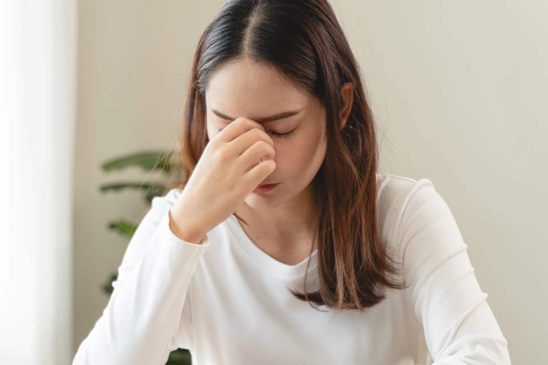 Woman pressing the bridge of her nose due to eye pain and discomfort