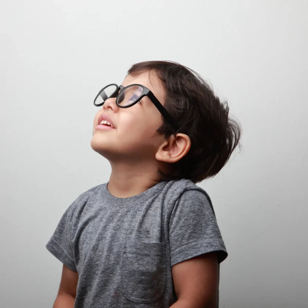 Young boy wearing glasses looking upwards