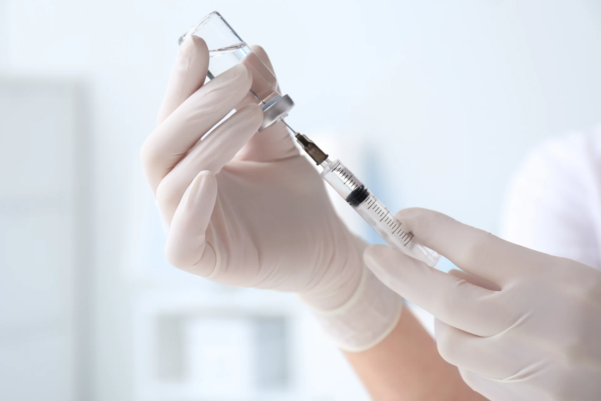 Doctor filling a syringe with medication from a vial